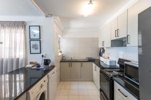 a kitchen with white cabinets and black appliances at Frinton on Sea 2 in Ballito +8 photos