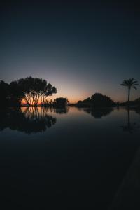 a sunset over a body of water with trees at Rakalia Pure Living Sicilian Retreat in Marsala