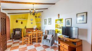 a living room with a table and chairs and a television at Villa Las Flores Frigiliana by Ruralidays in Frigiliana
