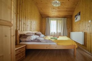1 dormitorio con 1 cama en una cabaña de madera en Biotour Camping & Restaurant en Ghimeş