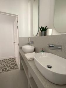 a white bathroom with a sink and a mirror at CasaWolhão LIBERDADE maison de pêcheur avec toit-terrasse in Olhão