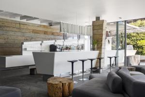 a lobby with a bar with stools and tables at POD Camps Bay in Cape Town