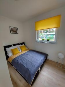 a bedroom with a bed with a yellow curtain and a window at Wave Apartment Pobierowo in Pobierowo