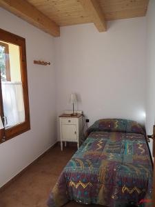 a bedroom with a bed and a table and a window at CA L'ANELLA (SALDES) in Saldés