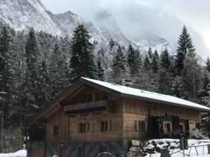 uma cabana de madeira na neve com montanhas ao fundo em Chalet S - 5 Sterne Luxus Ferienhaus direkt am Eibsee und Zugspitze em Grainau