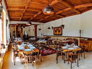 un ristorante con tavoli e sedie in legno in una stanza di Vardzia Resort a Vardzia
