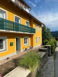 żółty budynek z balkonem na boku w obiekcie Ferienwohnung, wenige Minuten vom Wörthersee w mieście Schiefling am See