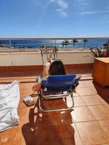 una mujer sentada en una silla mirando hacia el océano en Apartamento Playa del Faro en Garrucha