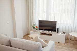 uma sala de estar com um sofá branco e uma televisão de ecrã plano em Modern Trindade by Homing em Porto