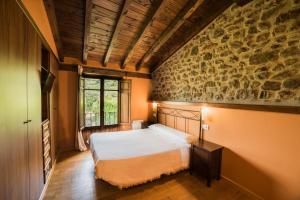 een slaapkamer met een bed en een stenen muur bij Mirador De Picos in Aliezo