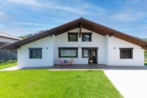 a white house with a wooden roof and green grass at Fidalsa North Style in Arosteguieta