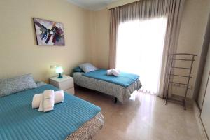 sypialnia z 2 łóżkami pojedynczymi i oknem w obiekcie Jardines de Nueva Galera w mieście Estepona