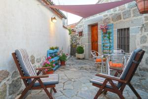 Casa Rural El Berrueco في Robledillo: فناء فيه كراسي ومظلة وطاولة
