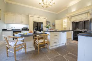 cocina con armarios blancos, mesa y sillas en Eslington East Wing en Alnwick