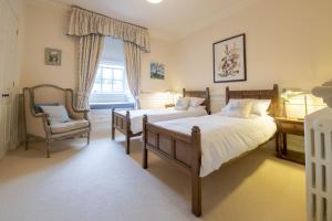 a bedroom with two beds and a chair and a window at Eslington East Wing in Alnwick