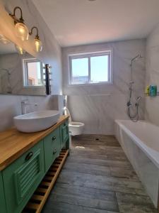 shirly three bedroom house في هرتسليا: حمام مع حوض وحوض استحمام ومرحاض