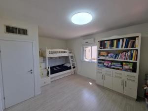 shirly three bedroom house في هرتسليا: غرفة مع غرفة مع رف كتاب