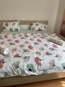 - un lit avec une couette et des fleurs rouges dans l'établissement Liliána Apartman Siófok, à Siófok