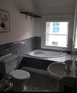 a bathroom with a tub and a toilet and a sink at Shop Street Apartment in Galway