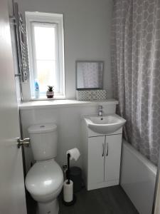 a bathroom with a toilet and a sink and a window at Delight Apartment, Close to Excel, London City Airport & O2! in London