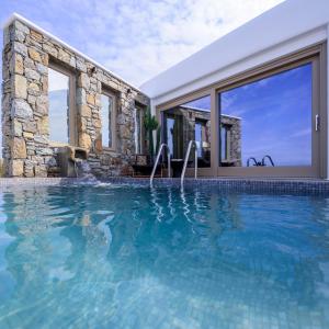 a swimming pool in front of a house at Vrachos Suites Mykonos in Mikonos