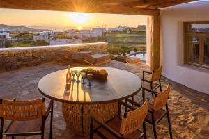 a table and chairs on a patio with the sunset at Vrachos Suites Mykonos in Mikonos
