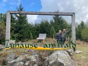 two people standing on a sign that reads wellness and well at Zuhause Am Wald in Brilon