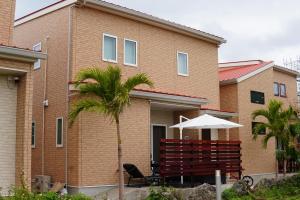 a brick building with a chair and an umbrella at きくのこ3缶ヴィラ＆テラス　 in Miyako Island