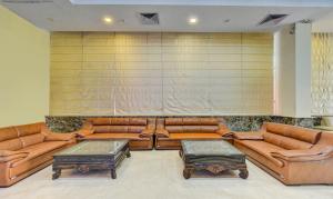 a living room with brown leather couches and tables at Treebo Trend Elysee - Patel Nagar in Dehradun