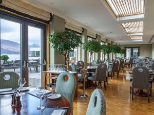 un restaurante con mesas, sillas y ventanas en The Europe Hotel & Resort, en Killarney