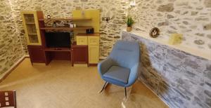 a blue chair in a room with a television at VILLA PENELOPE in Tourlotí