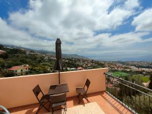 uma varanda com uma mesa e cadeiras e um guarda-sol em Costa Residence Funchal View em Funchal