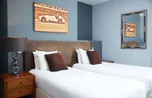 奇切斯特的住宿－Trents by Greene King Inns，两张位于酒店客房的床,墙上有一辆汽车