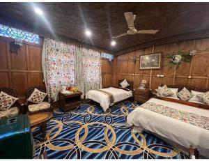 a bedroom with two beds and a ceiling fan at House Boat Shahnama, Dal Lake in Kārapur