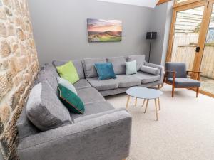 a living room with a gray couch and a table at 1 Barley Cottages in Matlock