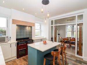 a kitchen with white cabinets and a blue island at 1 Barley Cottages in Matlock