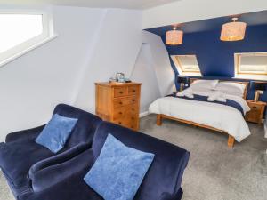 a bedroom with a bed and a couch with blue pillows at 1 Barley Cottages in Matlock