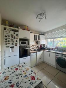 a kitchen with white appliances and a table in it at Cozy Room near City Centre in Manchester