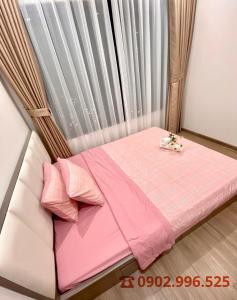 a small bed in a room with pink sheets and pillows at Vinhomes Grand Park Quận 9-Bống House in Long Bình