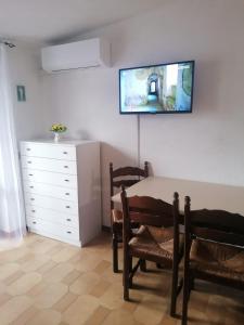 a room with a table and chairs and a tv on the wall at Аppartamenti vicino al mare in Scalea