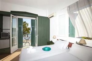 a bedroom with a white bed and a balcony at Ancora Hotel in Poros