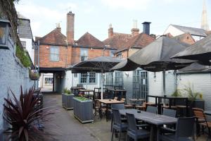 an outdoor patio with tables and chairs and umbrellas at Trents by Greene King Inns in Chichester