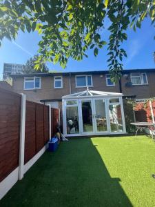 a backyard with an enclosed yard with green grass at Cozy Room near City Centre in Manchester