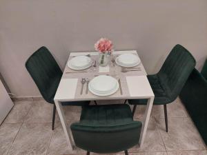 uma mesa com cadeiras verdes, pratos e flores em Emerald home em Ixia