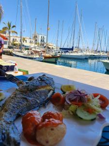 a meal of fish and vegetables on a plate next to a marina at Very Romantic Seaview Apartment Patalavaca Mogán with Warm Pool in Patalavaca