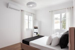 una camera da letto con pareti bianche e un letto con cuscini bianchi di Old Port Spetses Mansion a Spetses