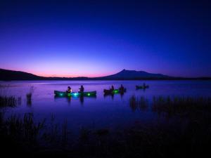 um grupo de pessoas em barcos em um lago à noite em Hakodate-Onuma Prince Hotel em Nanae