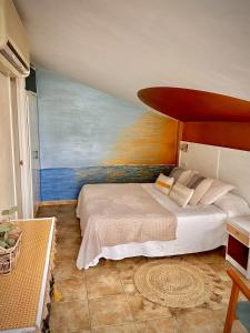 1 dormitorio con 1 cama con una pintura en la pared en La Muntanya, en Llafranc