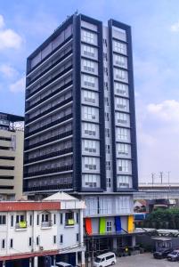 Amaris Hotel Kalimalang في جاكرتا: مبنى أسود طويل مع سيارات متوقفة أمامه