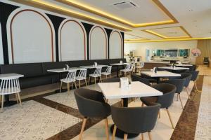 a dining room with tables and chairs and windows at M CASA HOTEL PATTAYA in Pattaya South